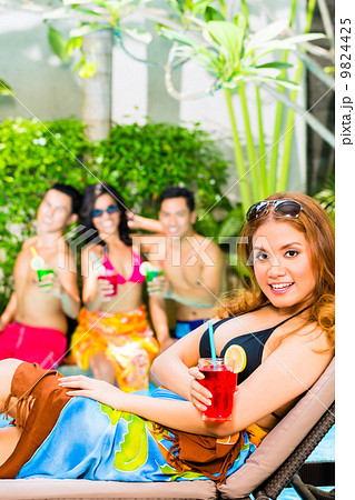 Asian friends partying at pool party in hotel 9824425