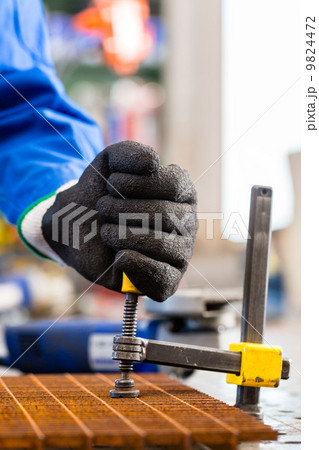 Workshop craftsman clamping metal on workbench 9824472