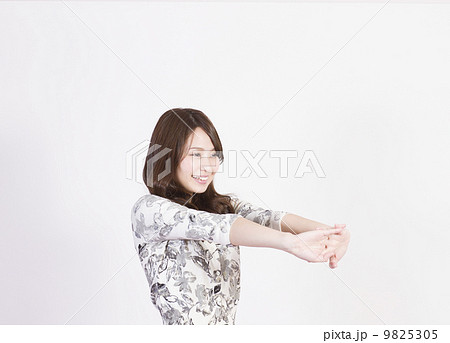 手を体の前で組んで伸ばす笑顔の若い女性の写真素材