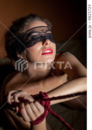 Beautiful girl blindfolded posing with hands bound 9825724