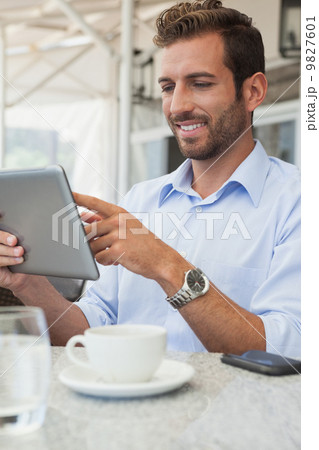 Cheerful young businessman working on tablet Cheerful young businessman working on tablet 9827601
