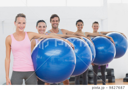 Fitness class holding exercise balls at fitness studio Fitness class holding exercise balls at fitness studio 9827687