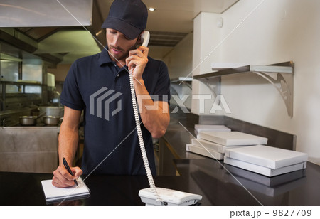 Handsome pizza delivery man taking an order over the phone Handsome pizza delivery man taking an order over the phone 9827709