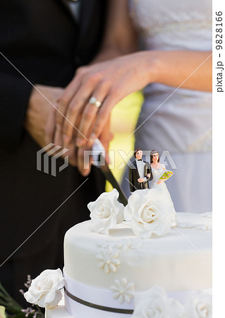 Mid section of a newlywed cutting wedding cake Mid section of a newlywed cutting wedding cake 9828166