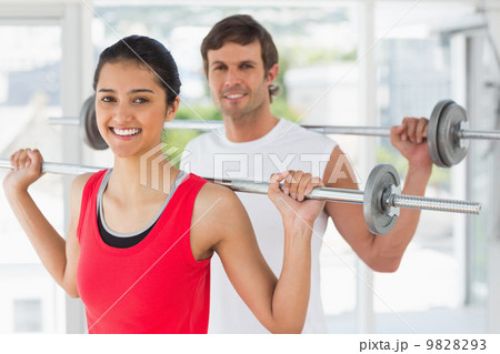 Fit young couple lifting barbells in gym Fit young couple lifting barbells in gym 9828293