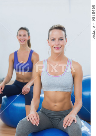 Sporty women sitting on exercise balls in gym Sporty women sitting on exercise balls in gym 9828469