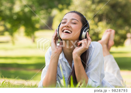 Cheerful young woman enjoying music in park 9828793