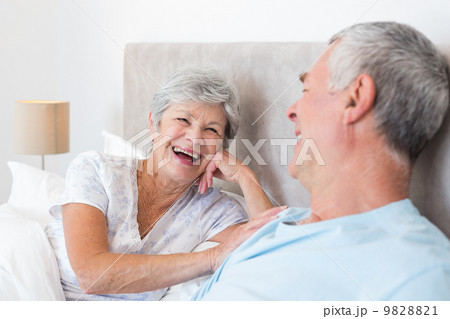 Senior woman looking at husband in bed 9828821