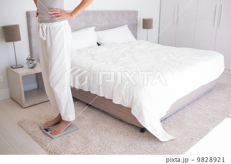 Low section of a woman standing on scale in bedroom Low section of a woman standing on scale in bedroom 9828921