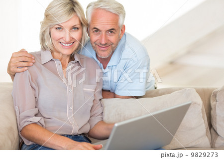 Happy mature couple using laptop on sofa 9829273