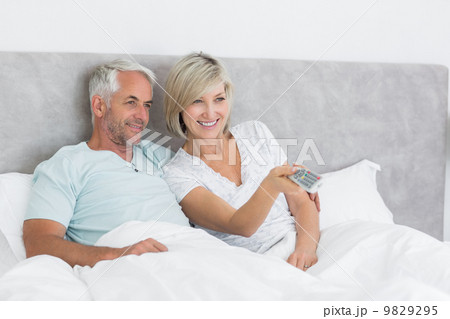 Happy couple watching tv in bed Happy couple watching tv in bed 9829295