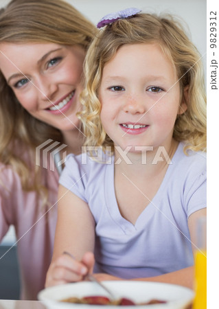 Girl having breakfast while sitting with mother Girl having breakfast while sitting with mother 9829312