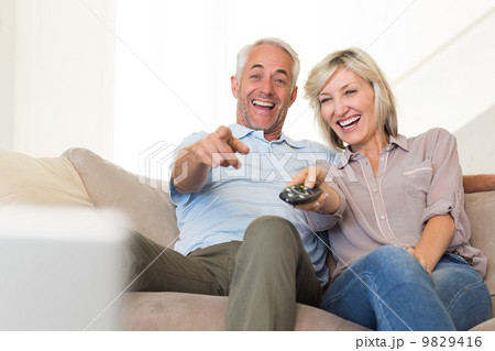 Cheerful couple watching tv at home Cheerful couple watching tv at home 9829416