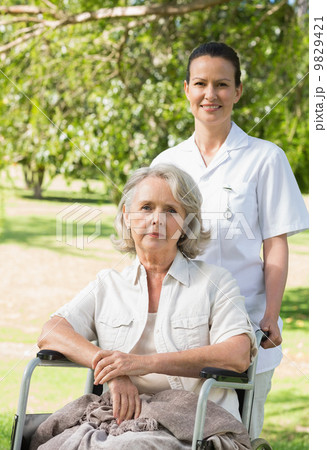 Woman with her mother sitting in wheel chair at park Woman with her mother sitting in wheel chair at park 9829421