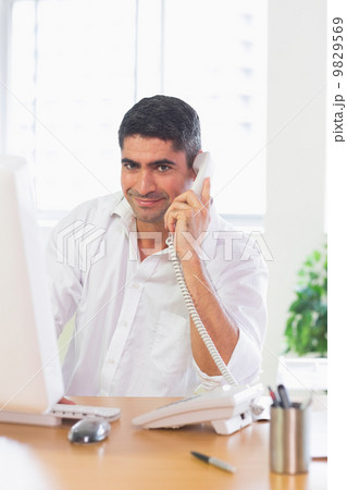Businessman using landline phone and computer 9829569