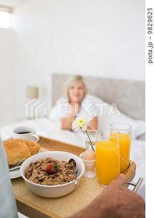 Woman sitting in bed with breakfast in foreground 9829625