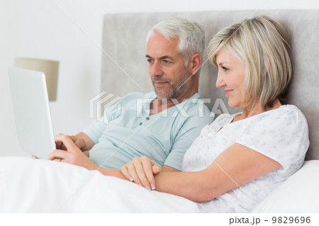 Concentrated couple using digital tablet in bed 9829696
