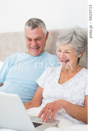Senior couple using laptop computer in bed 9829715