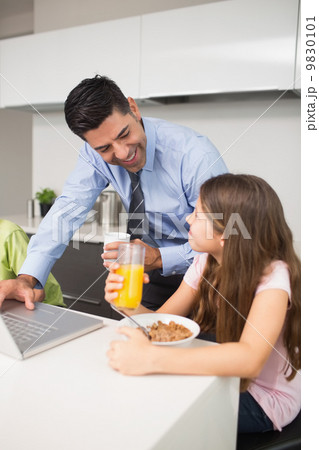 Father using laptop and kids having breakfast in kitchen Father using laptop and kids having breakfast in kitchen 9830101
