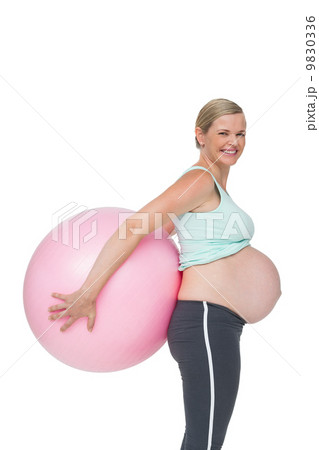 Happy pregnant woman holding pink exercise ball behind her back 9830336