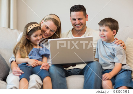 Family using laptop together on sofa 9830591