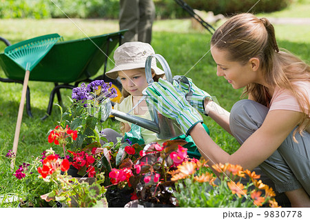 Mother and daughter watering plants at garden Mother and daughter watering plants at garden 9830778