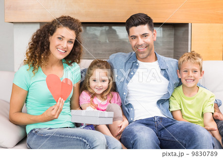 Smiling family sitting on sofa celebrating a birthday 9830789