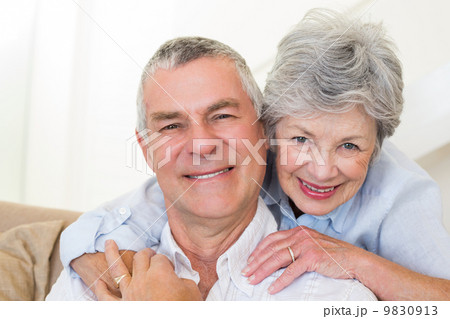 Senior woman embracing husband from behind Senior woman embracing husband from behind 9830913