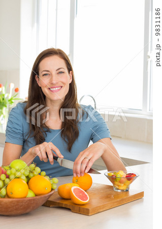 Portrait of a woman cutting fruits in kitchen Portrait of a woman cutting fruits in kitchen 9831186