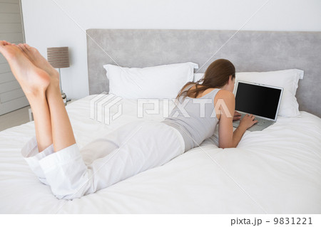 Relaxed young woman using laptop in bed Relaxed young woman using laptop in bed 9831221