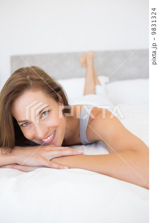 Pretty smiling young woman lying in bed 9831324
