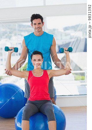 Male trainer helping woman with her exercises at gym Male trainer helping woman with her exercises at gym 9831392