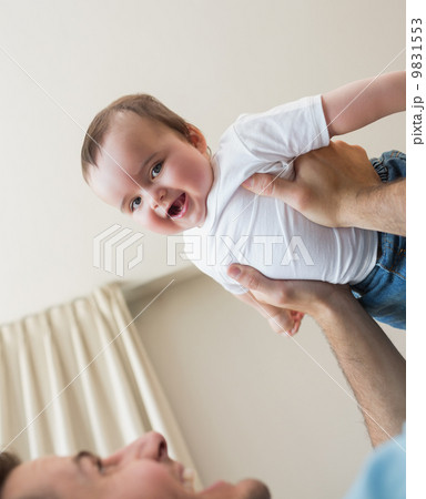 cheerful baby being carried by father 9831553