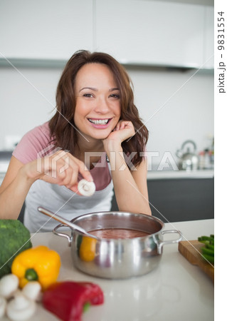 Smiling young woman preparing food in kitchen 9831554