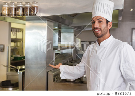 Smiling young chef looking at camera showing his workplace Smiling young chef looking at camera showing his workplace 9831672