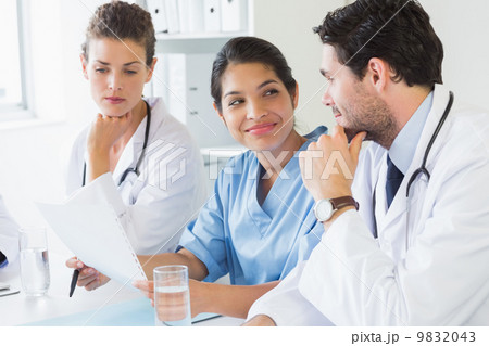 Doctors and nurse discussing over document Doctors and nurse discussing over document 9832043