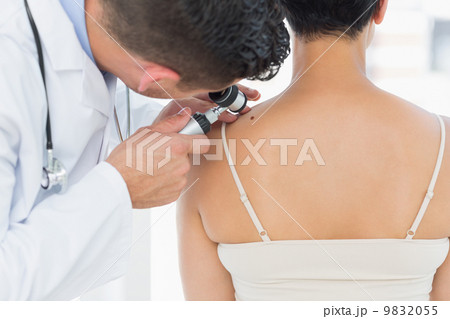 Dermatologist examining mole on back of woman 9832055