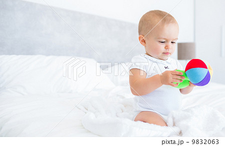 Cute baby with toy sitting on bed 9832063