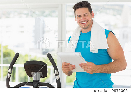 Smiling trainer with clipboard in gym 9832065