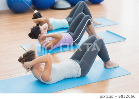 Determined women doing sit ups at fitness studio 9832066