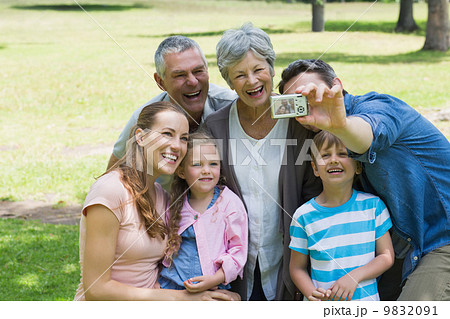 Man taking picture of extended family at park 9832091