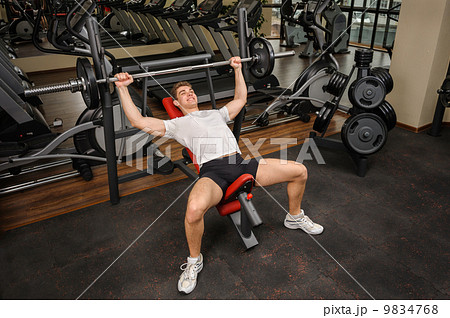 Young man doing Barbell Incline Bench Press workout in gym 9834768