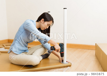 Asian woman using strew driver for assembling furniture 9843875