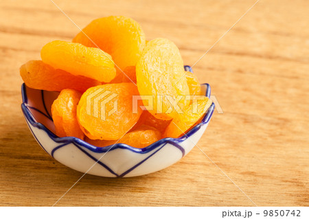 Bowl of dried apricots on wooden table background. Bowl of dried apricots on wooden table background. 9850742