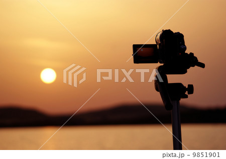 Silhouette of a camera taking videos of a sunset Silhouette of a camera taking videos of a sunset 9851901