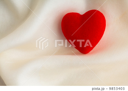 Red wooden decorative heart on white silk background. 9853403