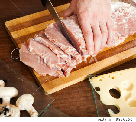 Hands cutting raw meat 9856250