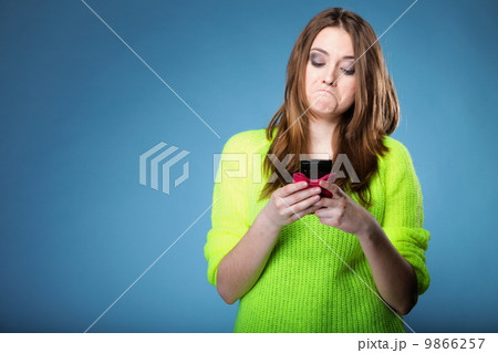 Funny girl with mobile phone reads message 9866257
