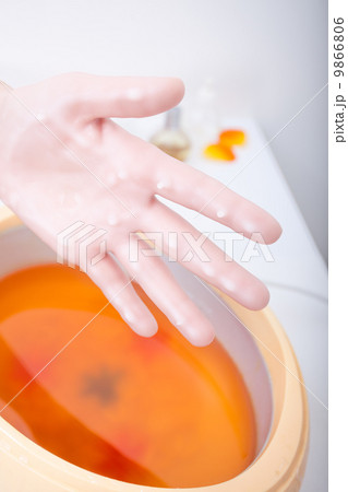 Female hand orange parrafin wax in bowl. Manicure beauty spa salon 9866806