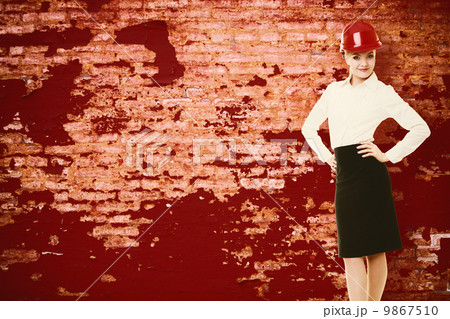 Female engineer woman architect in red safety helmet and red wall Female engineer woman architect in red safety helmet and red wall 9867510